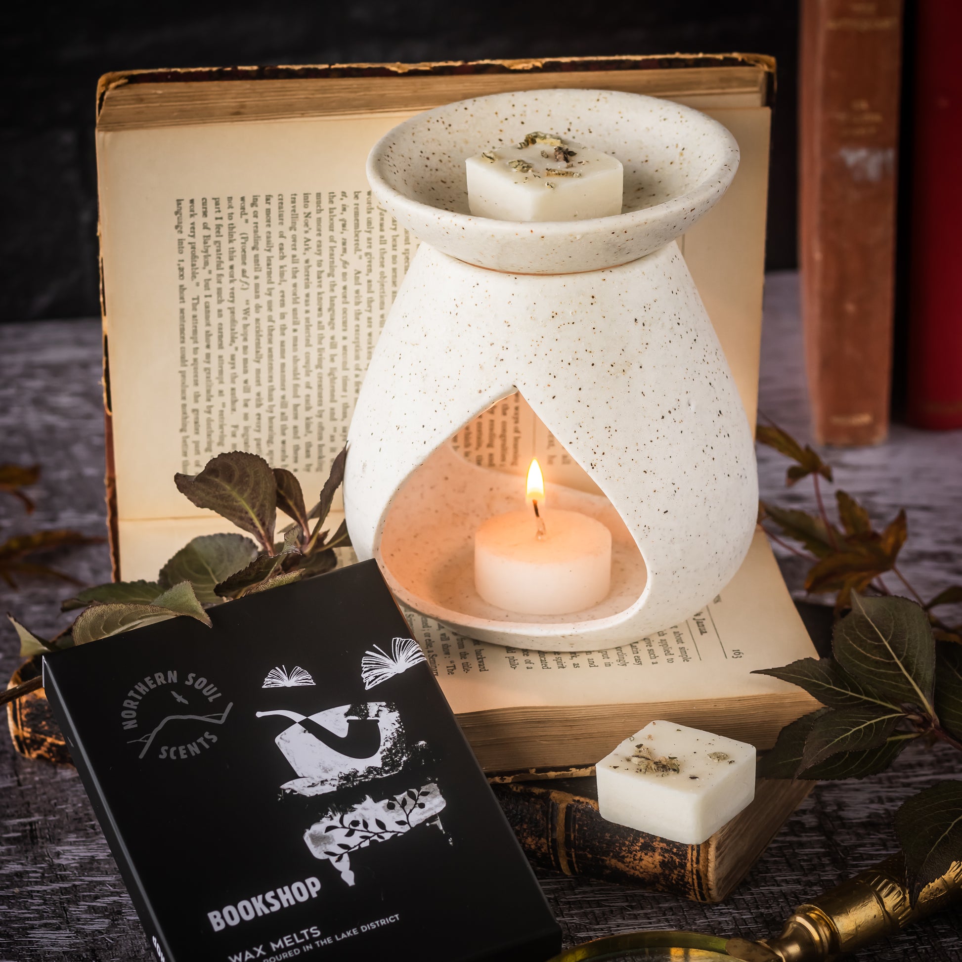 Bookshop scented wax melts shown in a rustic stoneware wax melter with candle