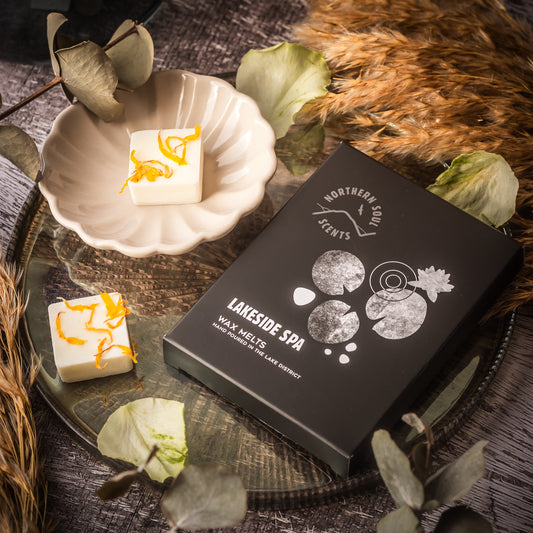 Lakeside Spa Scented Wax Melts: Indulge in the tranquil ambiance of a lakeside spa with these luxurious scented wax melts. Thoughtfully packaged in a plastic-free wax paper bag and enclosed in a cardboard sleeve adorned with a serene lily pad and water design on the front, these melts create a serene and refreshing atmosphere. Each wax cube is beautifully adorned with dried botanicals, adding a touch of natural elegance.